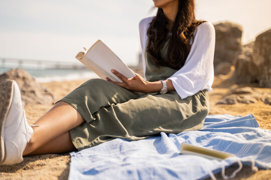 Beautiful young woman relaxing reading book at beach