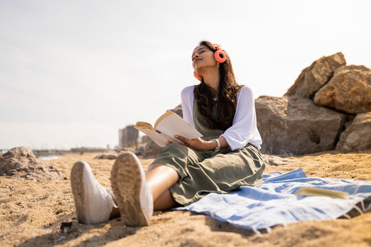 Beautiful young woman relaxing reading book at beach