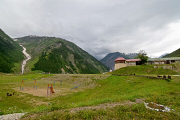 Landscape of a playground in a village surrounded by hills under a stormy sky