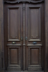 Background of a dark brown historical door with wooden decorations, which is made of wood