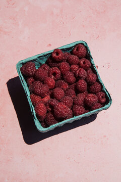 A box full of fresh raspberries in the sun