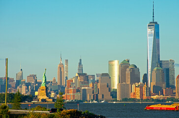 View of New York City's Manhattan island skyline, including Freedom Tower, Empire State Building, and Statue of Liberty, on a sunny day -02