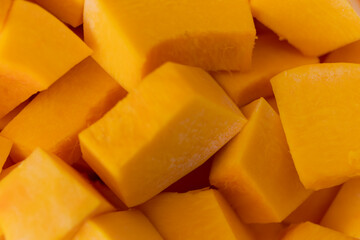 Diced Hokkaido pumpkin. Carotene-containing vegetables. Background in orange style.