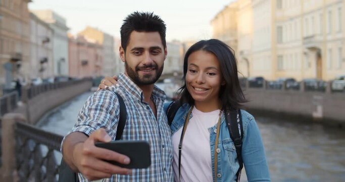 Happy multiethnic couple of tourists taking selfie in old city