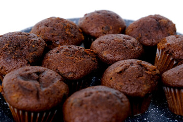 lot of chocolate muffins on a gray plate, high-calorie food concept, sweets , food pleasure, baby treat