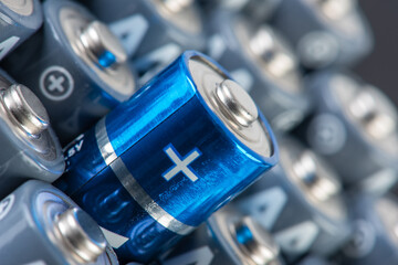 Stack of alkaline batteries size AA close up with focus on positive sign of one of them