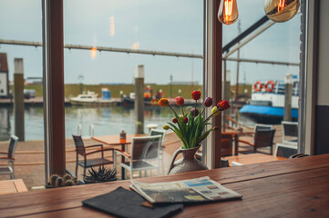 View from the window of the restaurant to the river, a vase with tulips on the window in the evening