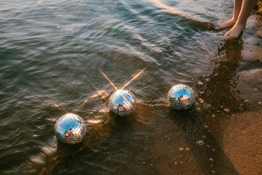 feet in the sea with mirror balls
