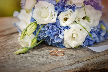 White and blue wedding bouquet with wedding rings on an old tree
