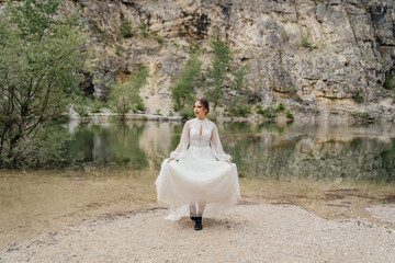 bride in black boots for mountain tourism on the shore of a mountain lake.