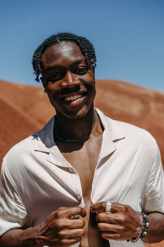 Portrait of a Man Buttoning Up His Shirt looking into the camera