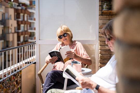 Senior friends having coffe and reading in balcony