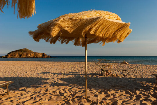 Fototapeta  Empty beach at sunset, umbrella  and chairs.