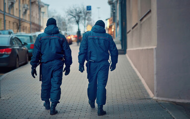 Police men on duty, patrol city street. Police in winter uniform with armor and baton patrolling in...