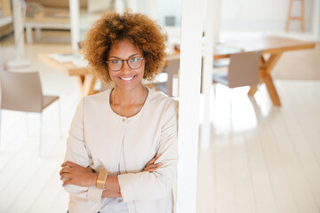 Portrait of woman leaning on column in office and smiling