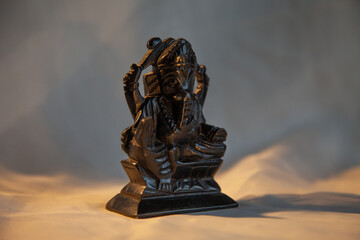 Statue of the Indian god Ganesha made of black stone on a light background