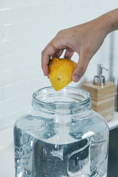 Hand Squeezing Lemon In A Water Jar