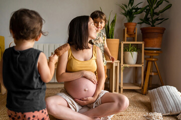 Gravid mum enjoying with her children at home