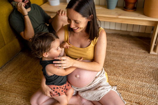 Pregnant mum relaxing holding her little son at home