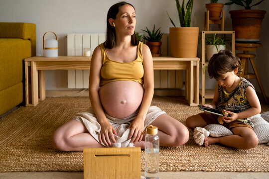Pregnant mother with her son at home using electronics