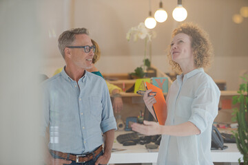 Colleagues talking and smiling in office, holding documents