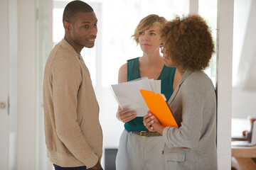 Colleagues talking and smiling in office, holding documents