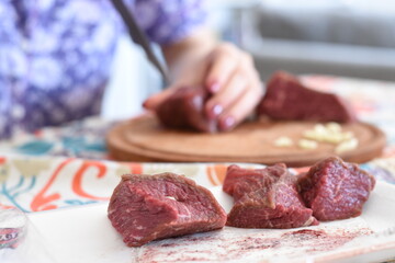 a young woman cutting up pieces of meat and putting garlic on it