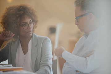 Obraz premium Two office workers talking at desk using laptop