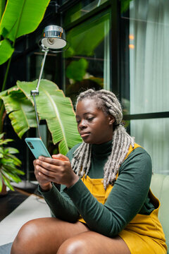 Black Young Girl With Phone On A Couch In A Workplace. 