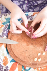 a young woman cutting up pieces of meat and putting garlic on it