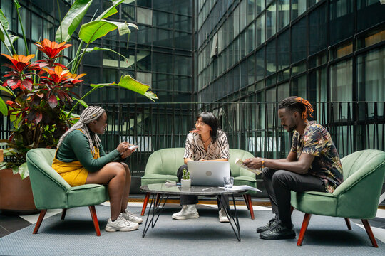 Three Colleagues Sitting In A Coworking Workplace. 