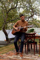 Obraz premium young man sits at the table and plays the guitar