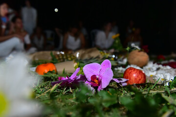 flowers thrown as an offering in religious ritual, cult of the orixás, spiritual ritual with flowers at night, mystical gathering and ceremony, peaceful spiritual offering, meditative and sacred space