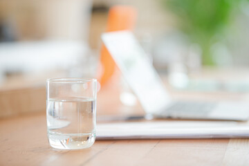 Close up of workplace with laptop and glass on desk