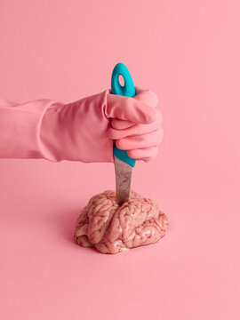 Surrealist still life of a hand stabbing a brain
