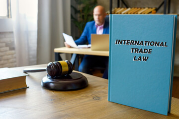 Attorney holds INTERNATIONAL TRADE LAW book. International trade law includes the rules and...