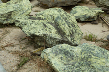 The stone is green. A piece of rock in the park. Rock.