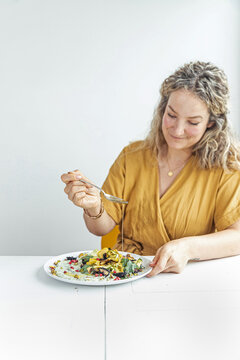 Young woman drizzling oilve oil on plate of salad