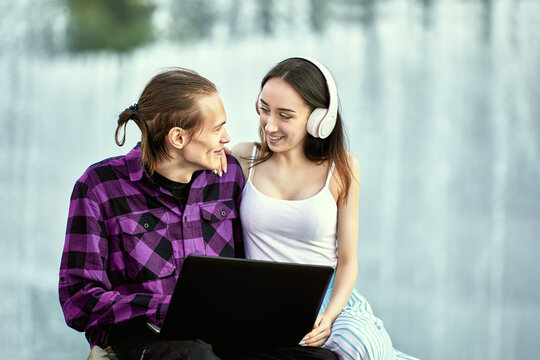 Young couple uses laptop outdoors during romantic date.