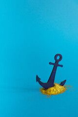 An anchor driven into a shiny gold powder. Feel gold on minimal creative blue background. © Andjela