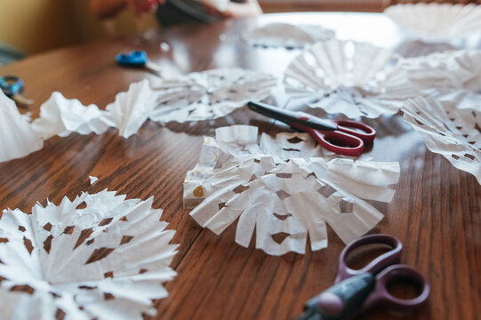 Paper snowflakes scattered around table. 
