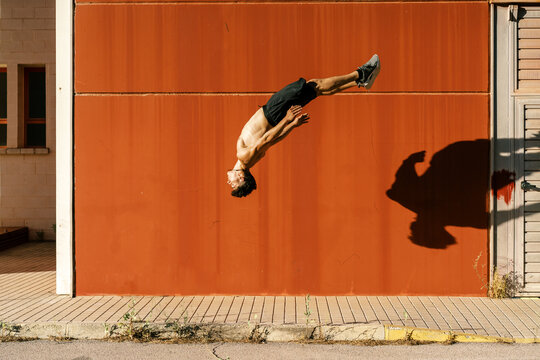Agile sportsman doing back jump trick on street