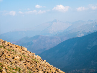 Layers of rock, mountains, and clouds in a colorful landscape image of the Rocky Mountains.