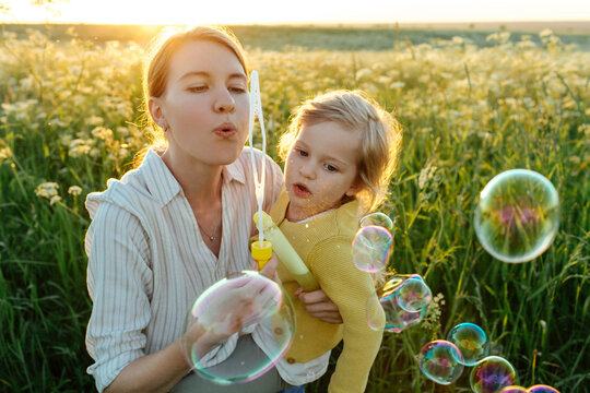 Mother blowing soap bubbles with daughter 