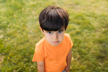 Funny child in t shirt on meadow with sad expression