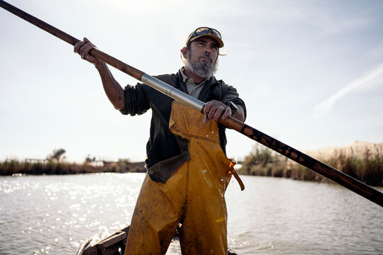 Front view of a fisherman standing in a boat using a push pole to move with his boat
