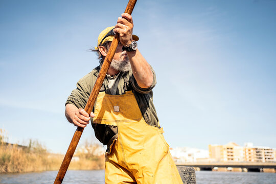 Low angle view of a fisherman standing in a boat using a push pole to move with his boat