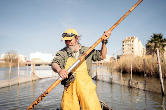 Front view of a fisherman standing in a boat using a push pole to move with his boat