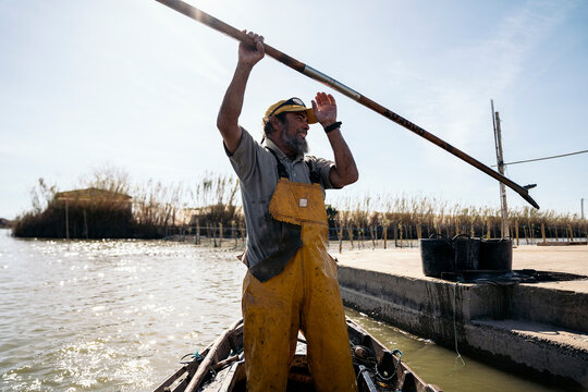 Fisherman with a long wooden pole in a boat