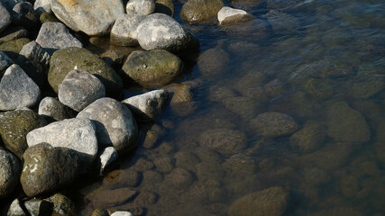 The stones and pebbles on the river bank, some are submerged in water